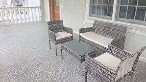 A covered outdoor seating area with wicker furniture and a glass table. - Chelsea Chalet - 4BR, Comfortable Stay Near It All (Atlantic City)