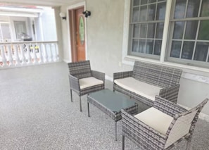 A covered outdoor seating area with wicker furniture and a glass table. - Chelsea Chalet - 4BR, Comfortable Stay Near It All (Atlantic City)