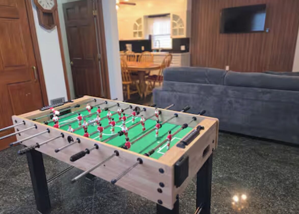 A foosball table in a room with a sofa and a television.