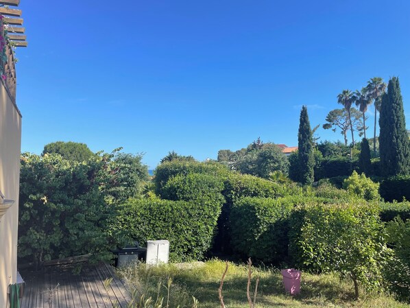 A garden with various trees and shrubs, a wooden deck, and a white structure. - Vrbo Property (Cagnes-sur-Mer)