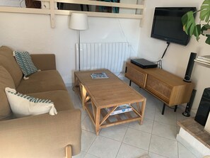 Een woonkamer met een bank, een houten salontafel, een televisie en een radiator.