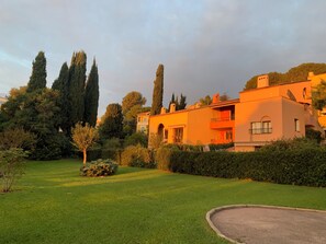 A residential building with a well-maintained lawn, tall trees, and a clear sky. - Vrbo Property (Cagnes-sur-Mer)