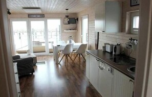 Une cuisine moderne avec un coin repas, de grandes fenêtres et une vue sur l’extérieur.