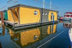 Ein festliegender Hausboot mit Treppe, Tür und Fenstern.