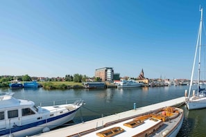 Un port de plaisance avec des bateaux amarrés, un bâtiment en arrière-plan et un ciel dégagé.