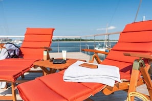 Une terrasse avec des chaises longues rouges, une table en bois et une serviette blanche.