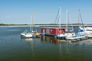 Een jachthaven met diverse boten afgemeerd, een rood gebouw en een steiger die het water in loopt.