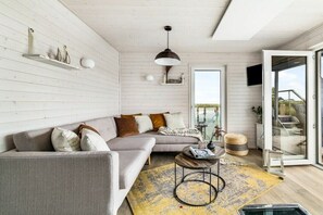 A modern living room with a sofa, a coffee table, and a large window. - Holiday home in Kragenaes with terrace (Kragenaes)
