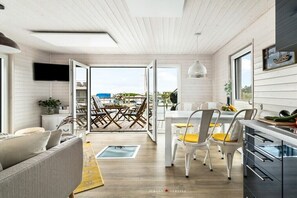 A modern interior with a dining area, kitchen, and open space leading to a balcony. - Holiday home in Kragenaes with terrace (Kragenaes)