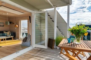 Un interior moderno con piso de madera, un sofá, una mesa y una puerta de vidrio que da al exterior.