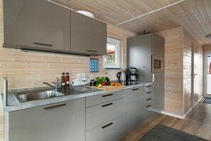 Una cucina moderna con pareti in legno, un lavello in acciaio inossidabile e un piano di lavoro con diversi oggetti.