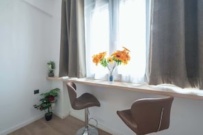 A room with a window, a vase with flowers, a potted plant, and two chairs. - Studio King Bed&Workspace- Weekend Noise (Athina)