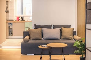A modern living room with a sofa, a small round table, and a potted plant. - Studio King Bed&Workspace- Weekend Noise (Athina)
