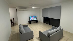 A living room with a flat-screen TV, grey sofas, a ceiling fan, and a tiled floor. - Family-friendly home—feel right at home. (Crestmead)