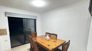 A dining area with a wooden table and chairs, a sliding glass door, and a tiled floor. - Family-friendly home—feel right at home. (Crestmead)