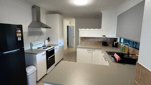 A modern kitchen with white cabinets, a black refrigerator, a stove, and a sink. - Family-friendly home—feel right at home. (Crestmead)