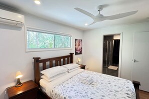 A bedroom with a bed, bedside lamps, a ceiling fan, a window, and a door leading to a bathroom. - Pool House with free parking and air conditioning (Marsden)