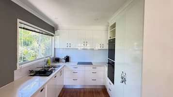A compact kitchen with white cabinetry, a window, and a built-in oven.