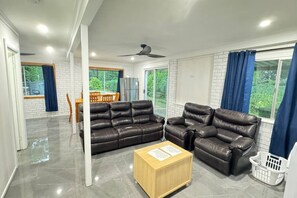 Un salon moderne avec un canapé d’angle, une table basse en bois et un ventilateur de plafond.
