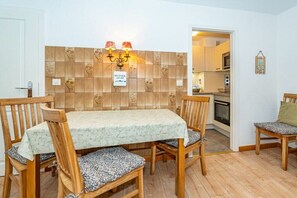 Uma área de refeições com mesa e cadeiras, painel de azulejos e placa indicando um local para manteiga.