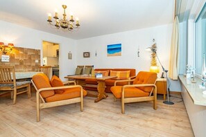 Een gezellige woonkamer met houten meubels, een kroonluchter en uitzicht op zee.