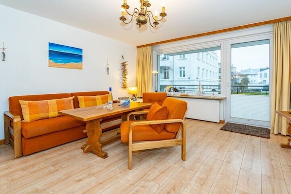 Une pièce comprenant un canapé, une table en bois, une chaise, une fenêtre donnant sur un beau paysage et un lustre.