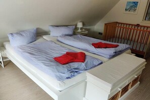 A bedroom with two beds, a crib, a nightstand, and a painting on the wall. - Holiday apartment with 3 bedrooms (Prerow)