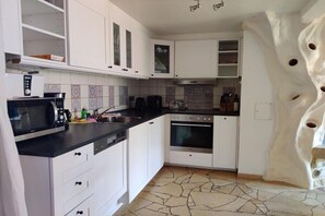 A kitchen with white cabinets, a microwave, a stove, and a sink. - Holiday apartment with 3 bedrooms (Prerow)