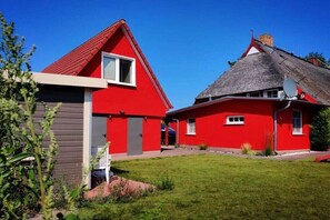 A red building with a grey roof, a satellite dish, and a small garden area. - Holiday apartment with 3 bedrooms (Prerow)