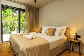 Una camera da letto con un letto, un comodino, una finestra con tende e vista sul verde.