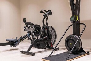 Un vélo d’appartement, un rameur et un appareil de musculation avec des poids.