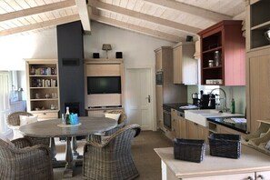 Een keuken met een eethoek, inbouwplanken, een televisie en een open haard.