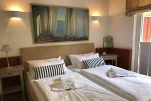 Een hotelkamer met twee bedden, een schilderij aan de muur en een klok op een nachtkastje.