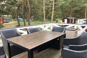 An outdoor deck with a table and chairs, surrounded by trees. - Prerow || beach house (Prerow)