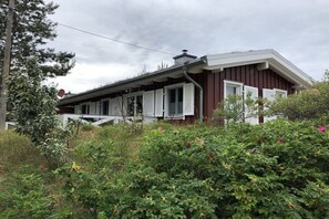 A single-story building with a porch, surrounded by dense shrubbery and trees. - Prerow || beach house (Prerow)