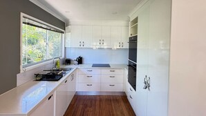 Uma cozinha compacta com armários brancos, uma janela e forno embutido.