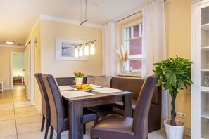 Un comedor con una mesa dispuesta para cuatro personas, una banca y una planta en maceta.