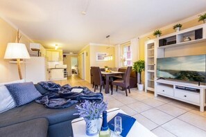 Een moderne woonkamer met een bank, televisie, eethoek en keuken.