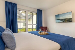 A bedroom with a bed, a chair, a painting, and a view of the outdoors. - One-bedroom apartment (Ostseebad Zingst a Darß)