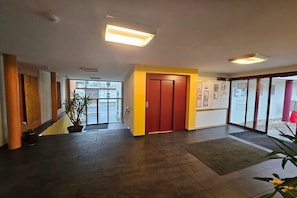 Un hall d’entrée spacieux avec une porte rouge, des plantes en pot et un escalier.