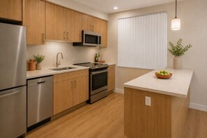 A modern kitchen with stainless steel appliances, wooden cabinets, and a central island. - The Vionelle Hotel (Toronto)