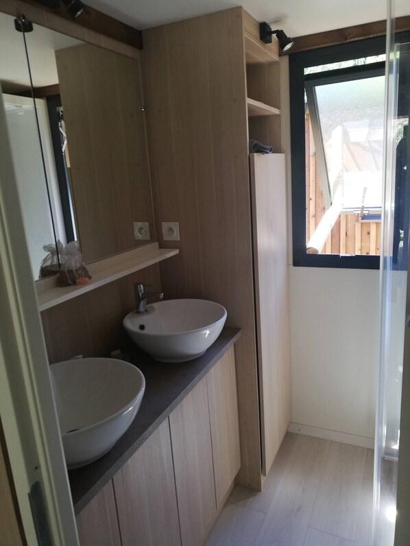 Un baño moderno con dos lavamanos, un espejo y un ventanal.