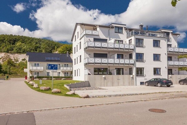 En byggnad med flera våningar, balkonger, en parkeringsplats och en skylt som visar var gångvägen går.