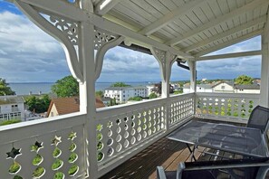 Un balcon abrité offrant une vue sur la mer, avec une table et des chaises.