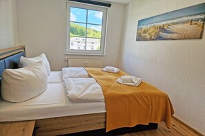 Ett sovrum med en s äng, ett fönster, en tavla och utsikt över en byggnad.