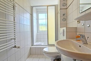 Ett badrum med toalett, handfat, spegel och fönster.