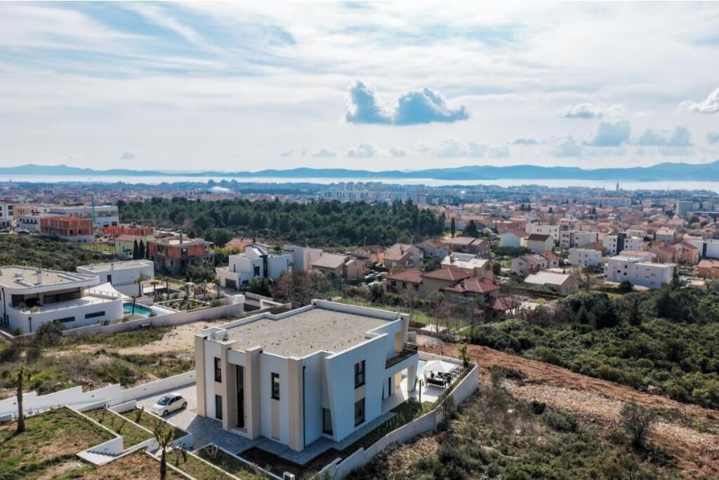 Un barrio residencial con casas modernas, una piscina y vistas a montañas distantes.