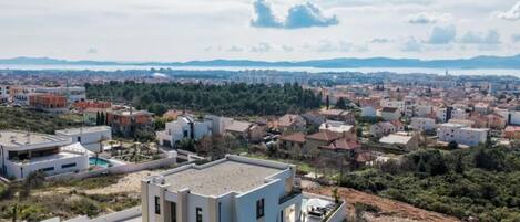 Un barrio residencial con casas modernas, una piscina y vistas a montañas distantes.
