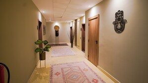 Un couloir avec des portes en bois, un tapis à motifs et un élément décoratif fixé au mur.