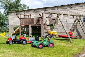 Un bâtiment doté d’une structure de jeu en bois, d’un toboggan et d’une balançoire.